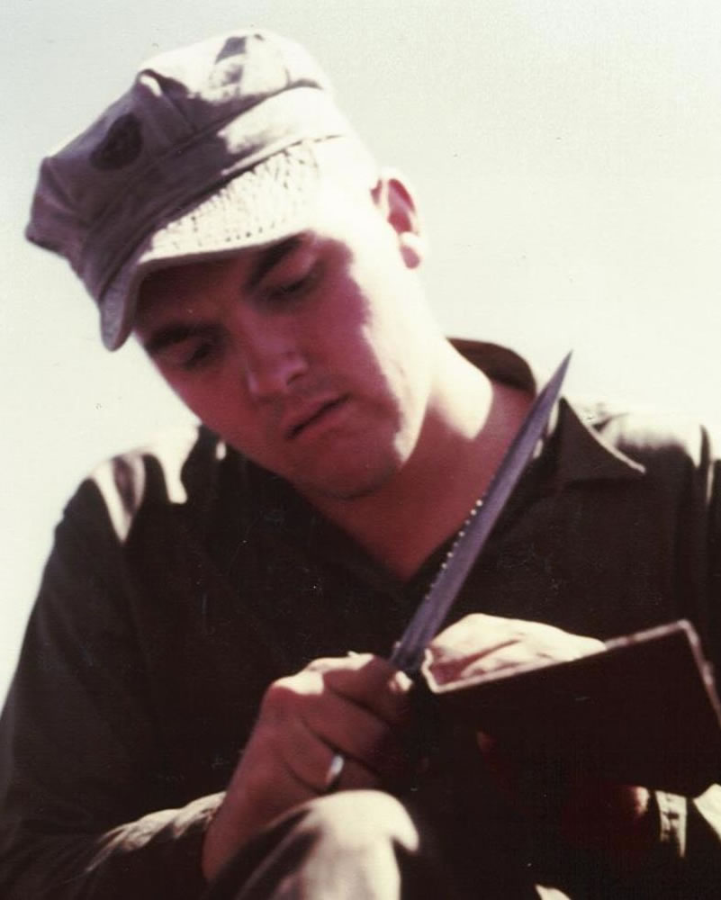 UDT operator sharpening his knife for cutting fish nets.