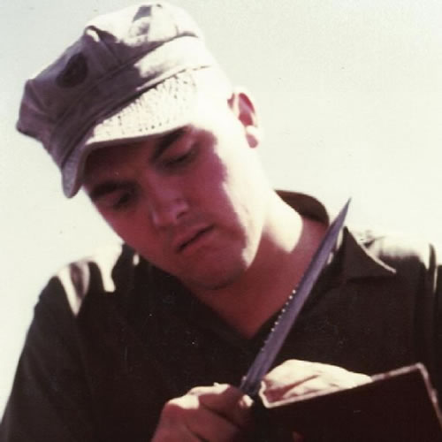 UDT operator sharpening his knife for cutting fish nets.